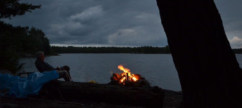 Campfire with night sky and lake.