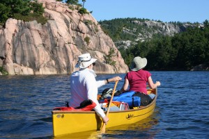 Yellow canoe paddling past pink rocks.