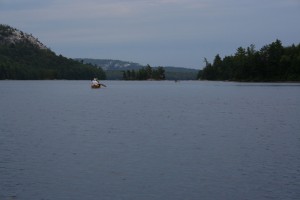 Canoes paddling up a lake with a dark sky