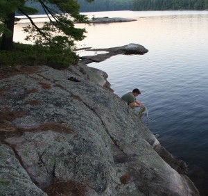 Man pumping water on a rock ledge.