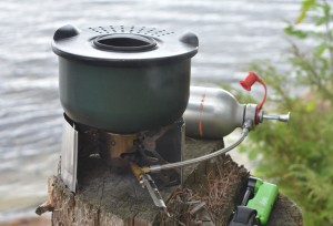 Pot on a camp stove above a lake.