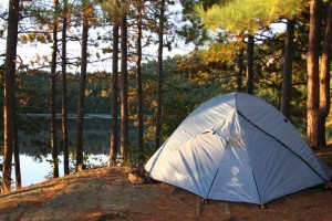 Tent with trees and lake in background.