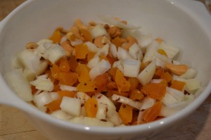 Onions, rice and fruit cut up in a bowl.