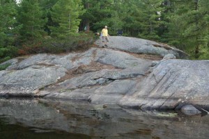 Man walking down rocks to the water.