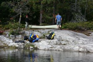 Couple with a white canoe and packs at the end of a portage