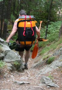 man on portage with paddles in hand