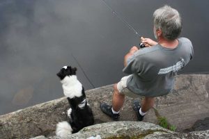 Dog beside man fishing