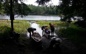 People loading canoes on shore