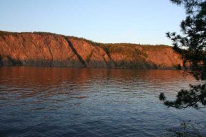 Red sun on rocks across water