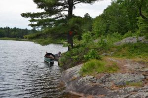 man on shore with feet on canoe