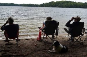 three people looking at the lake on a beach