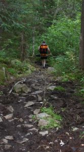 Man with barrel walking a rocky portage