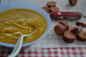 soup and sausae on red checked table cloth