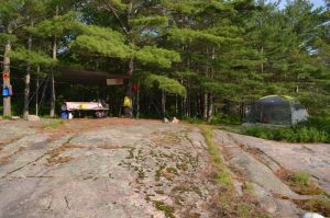 rocks, picnic table, tarp and a mesh tent