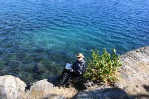 man reading beside blue water