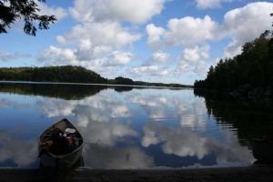 canoe on shore, clouds in water