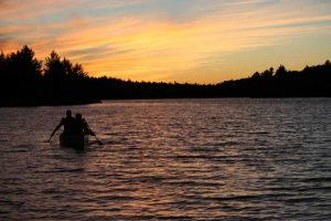 canoe paddlers on water at sunset