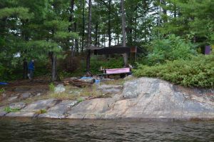 picnic table with red check table cloth on rocks from the water
