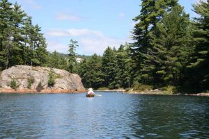 Canoe entering channel with rocks and trees.