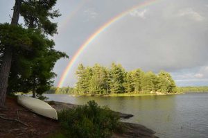 rainbow, over an island, with a white canoe on shore