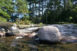 campsite from the water, large rock