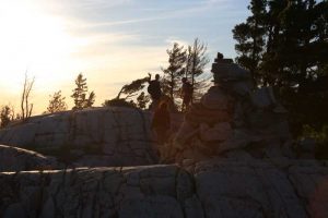 three people and a carin at dusk