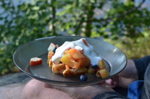 Man holding a plate with fruit salad and yougert