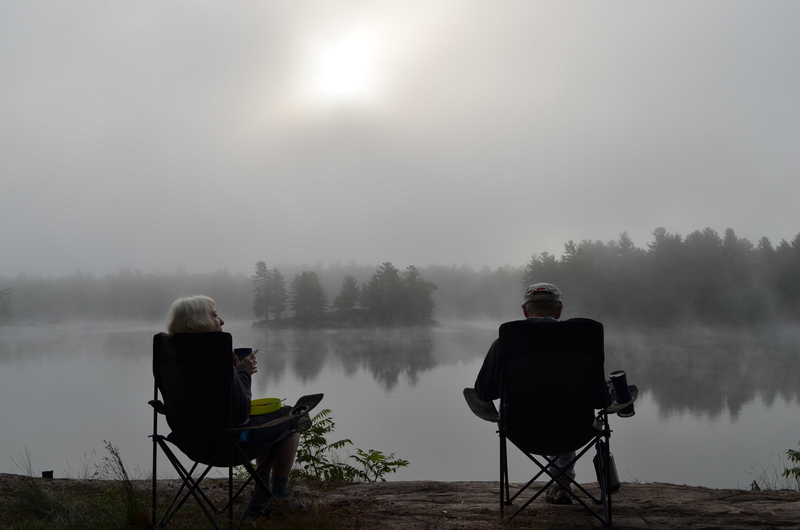 couple watching mist on lake from chairs
