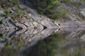 rock shore reflecting in the water