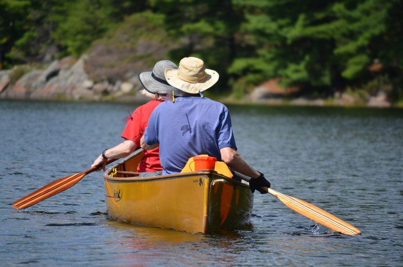two people in a yellow canoe with rocky shore