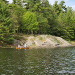 Canoe paddling past a rock campsite