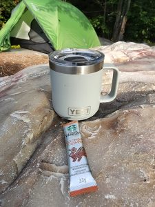 coffee mug on the rocks green tent