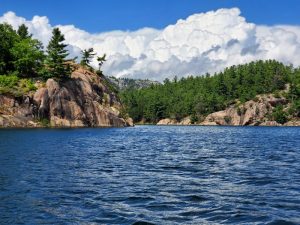 Blue water white puffy clouds red rock.